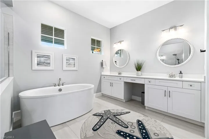 Bathroom featuring dual vanity, tile patterned floors, and a washtub