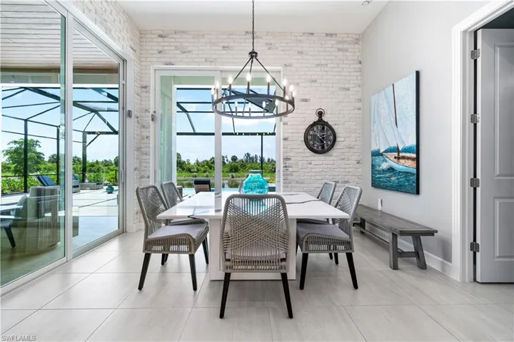 Tiled dining room featuring brick wall, a healthy amount of sunlight, and a chandelier
