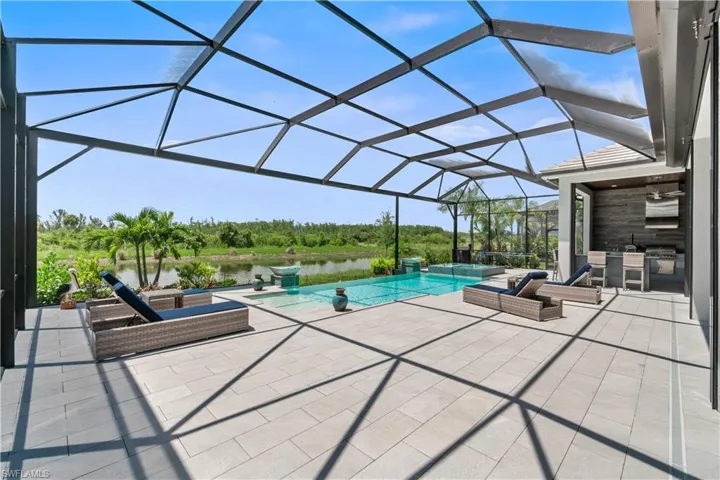 View of pool with a patio area, a water view, and glass enclosure