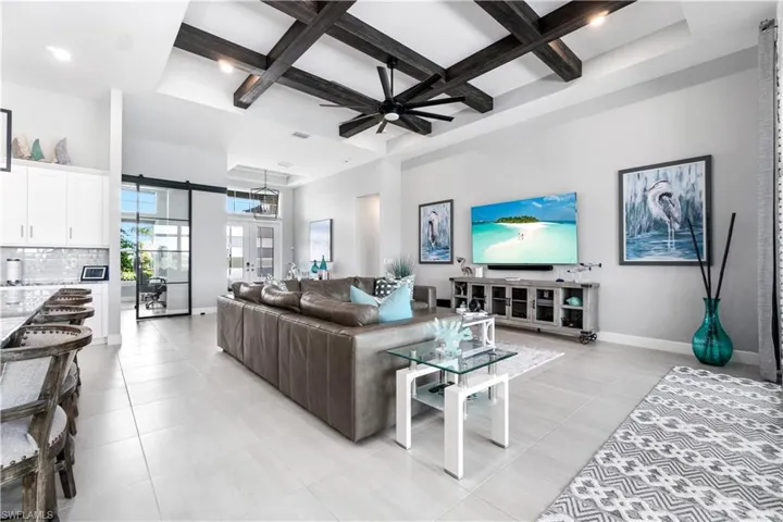 Tiled living room with beam ceiling, coffered ceiling, and ceiling fan