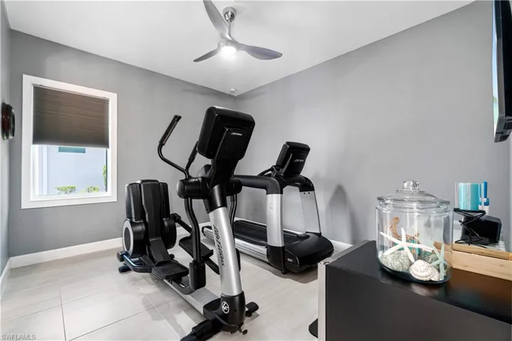 Workout area with light tile patterned flooring and ceiling fan