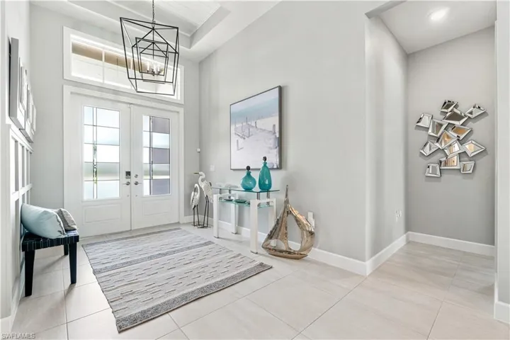 Entryway with a high ceiling, light tile patterned floors, french doors, and a chandelier