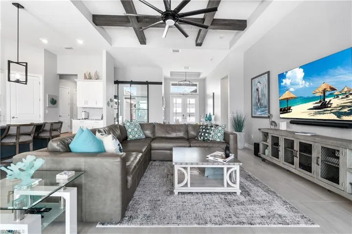 Tiled living room featuring beam ceiling, coffered ceiling, and ceiling fan