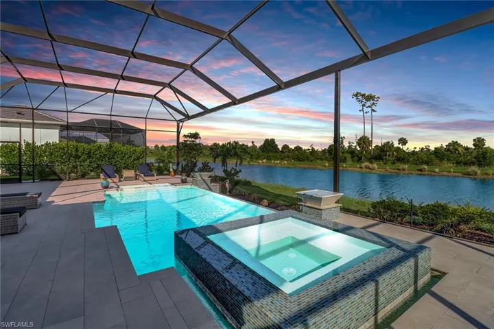 Pool at dusk featuring a patio, glass enclosure, and an in ground hot tub