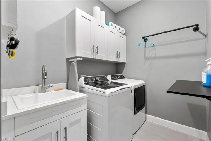 Laundry room with sink, separate washer and dryer, cabinets, and light tile patterned floors