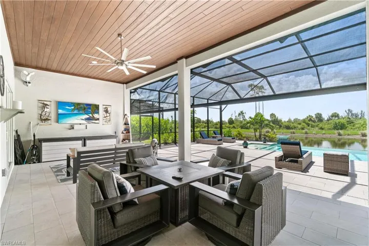 View of patio / terrace featuring a water view, ceiling fan, and glass enclosure