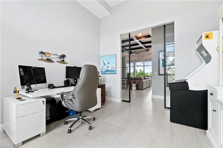 Home office with beam ceiling, light tile patterned flooring, and coffered ceiling