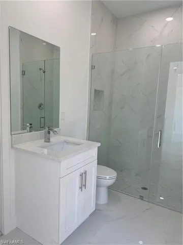 Bathroom with vanity, a shower with shower door, and toilet