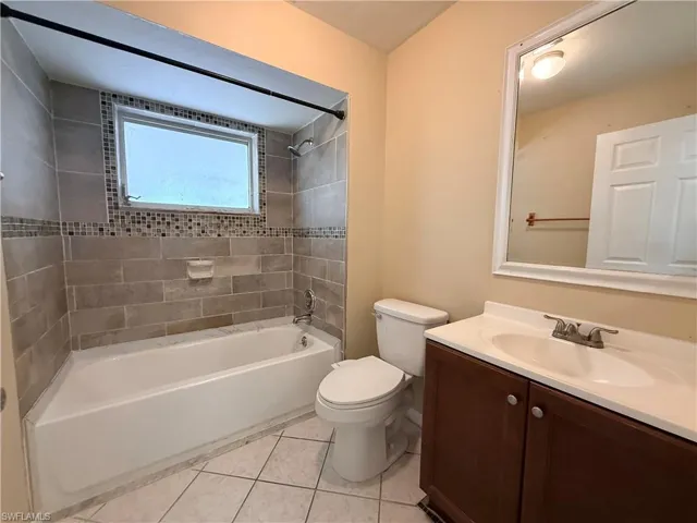Bathtub with subway tile surround, mosaic tile accent, and frosted window