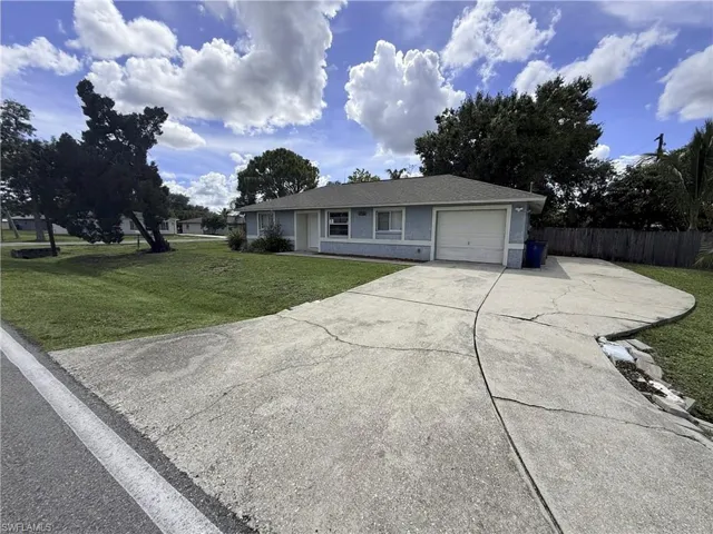 Single-story residence featuring light blue siding, a grey shingle roof, an attached garage, and a concrete driveway