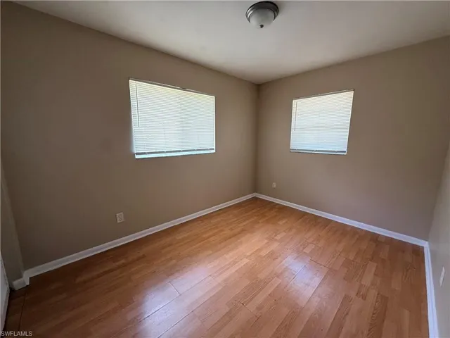 Wood-finish flooring, two windows with blinds, and neutral wall tones