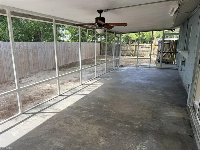Expansive screened-in porch with a concrete floor, ceiling fan, and access to a fenced yard