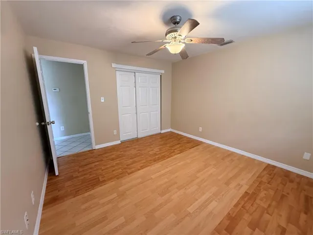 Wood-finish flooring with a ceiling fan light fixture and bi-fold closet doors