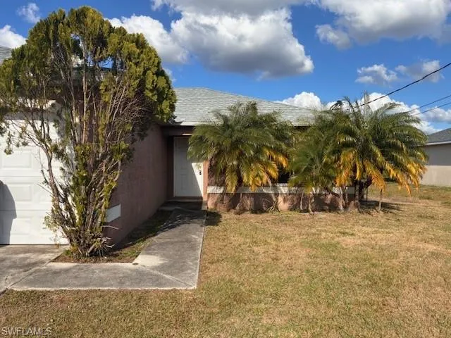 View of side of home featuring a lawn, an attached garage, and stucco siding