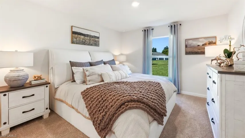 Model home. Bedroom featuring light colored carpet and baseboards