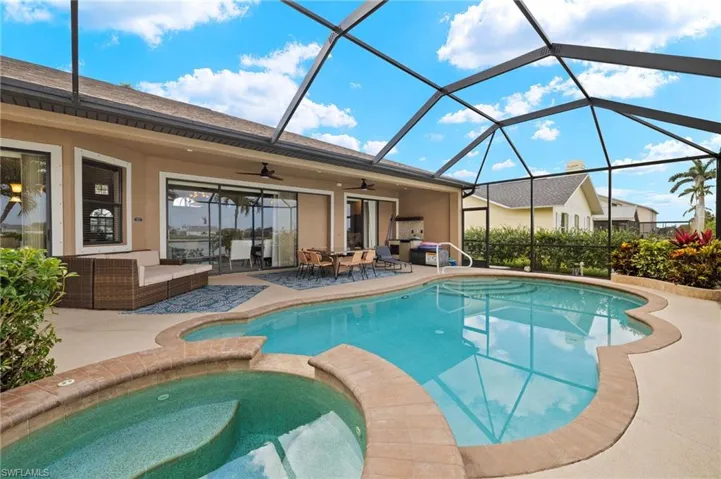 View of pool with a ceiling fan, a patio area, outdoor dining area, a pool with connected hot tub, and glass enclosure