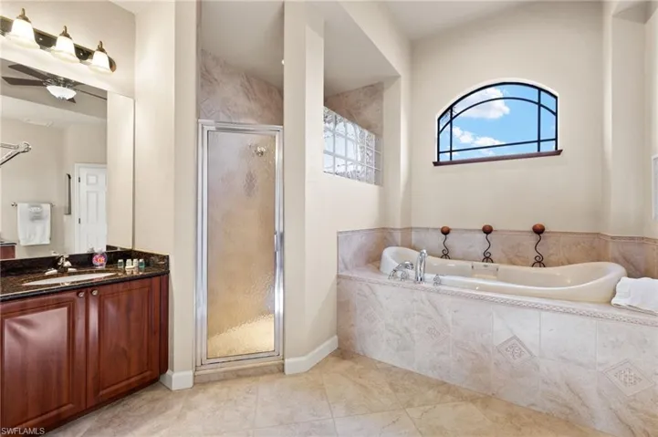 Full bathroom featuring vanity, a stall shower, a bath, baseboards, and tile patterned floors