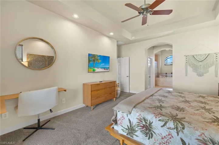 Bedroom with arched walkways, carpet floors, recessed lighting, a tray ceiling, and baseboards