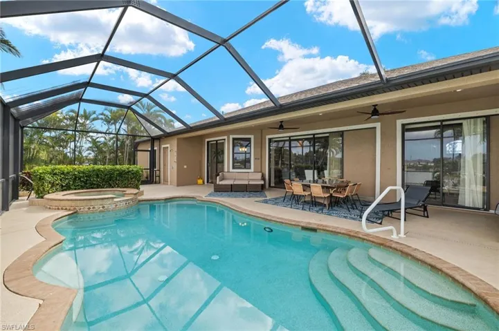 View of swimming pool with a ceiling fan, a patio, a pool with connected hot tub, and glass enclosure