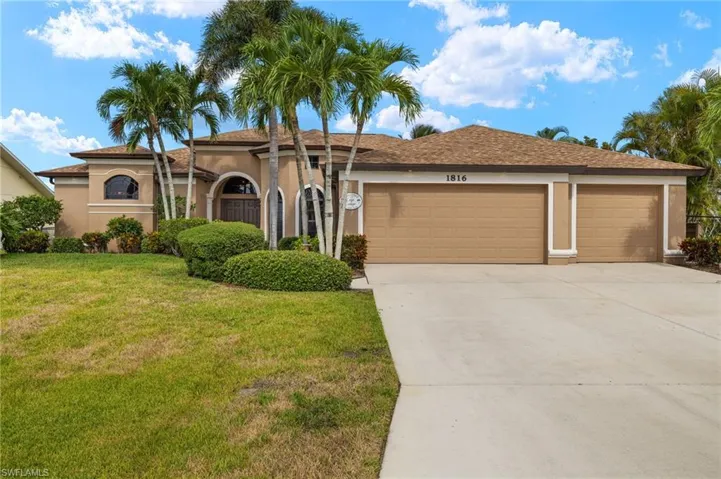 View of front of home with a garage, driveway, stucco siding, and a front yard
