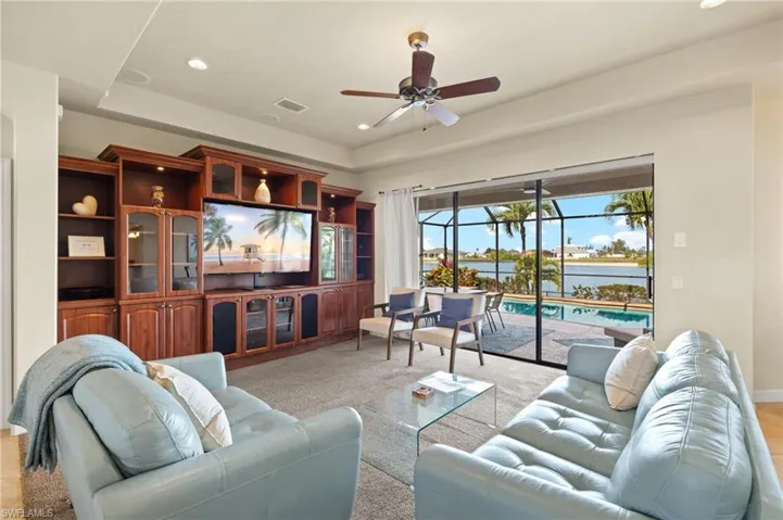 Living room with ceiling fan, recessed lighting, light colored carpet, a tray ceiling, and baseboards