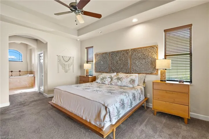 Bedroom featuring carpet floors, arched walkways, multiple windows, and recessed lighting