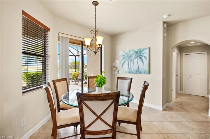 Dining area with arched walkways, a chandelier, light tile patterned floors, and baseboards