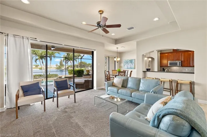 Living room with arched walkways, a water view, ceiling fan, baseboards, and recessed lighting