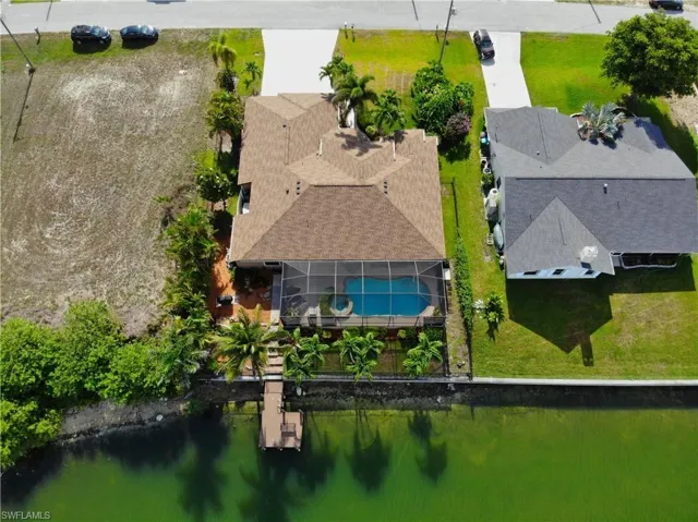 Aerial view of property and surrounding area featuring a pool area and a large body of water