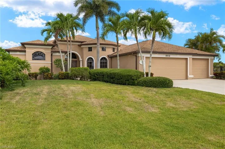 View of front facade with an attached garage, stucco siding, driveway, and a front lawn