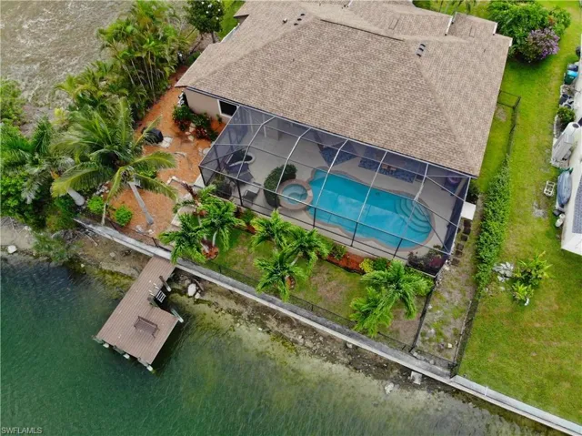 Aerial view of property and surrounding area featuring a pool area and a large body of water