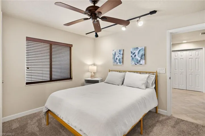 Carpeted bedroom featuring baseboards, rail lighting, ceiling fan, and tile patterned flooring