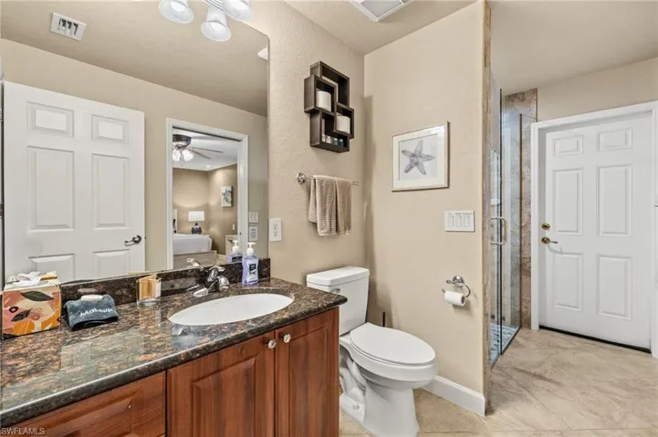 Full bath with a stall shower, ensuite bath, vanity, ceiling fan, and toilet
