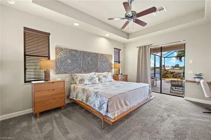Bedroom with access to outside, a raised ceiling, baseboards, dark colored carpet, and recessed lighting