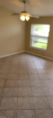 Spare room featuring a ceiling fan and tile patterned floors