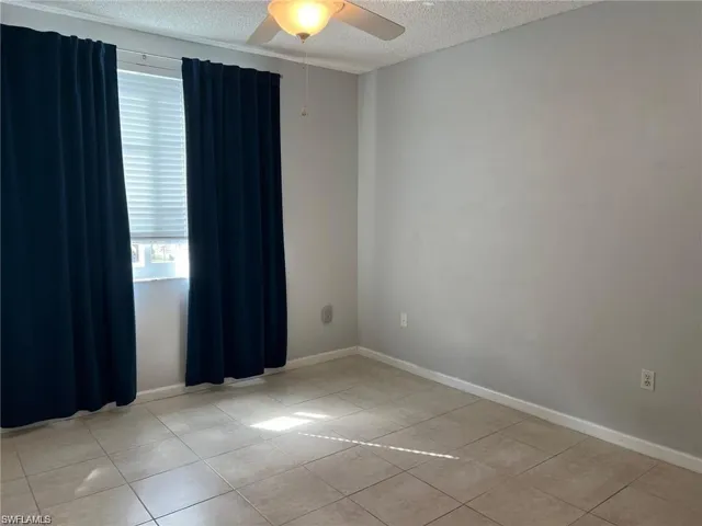 Unfurnished room featuring a textured ceiling, light tile patterned floors, and a ceiling fan