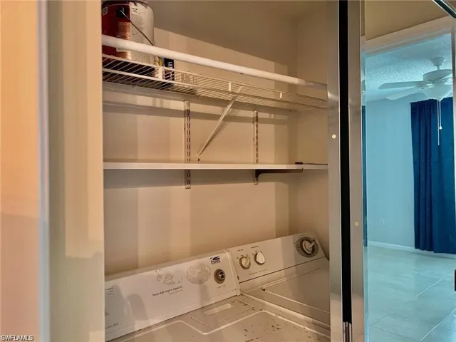 Laundry room with separate washer and dryer, light tile patterned floors, and ceiling fan