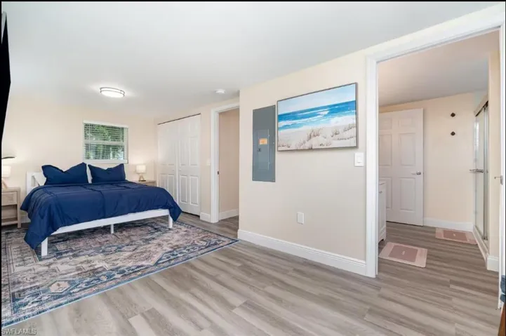 Bedroom with light wood-style flooring, electric panel, and a closet