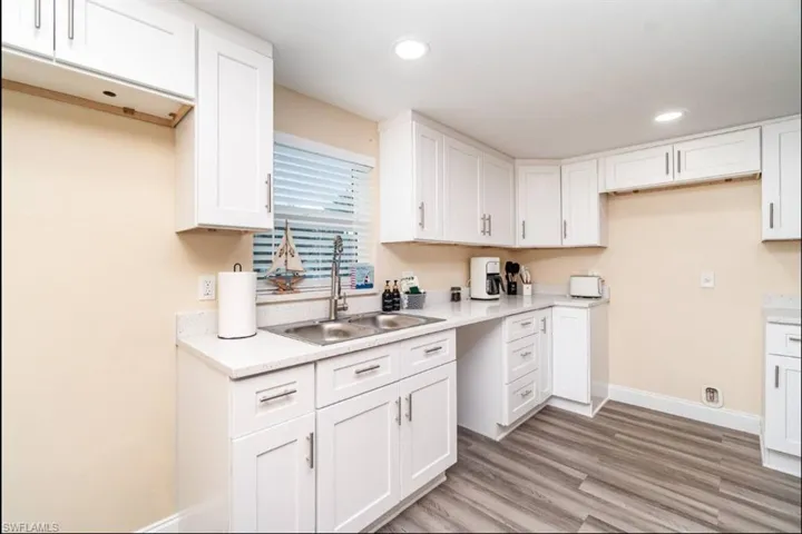 Kitchen with light wood finished floors, white cabinets, light countertops, and recessed lighting