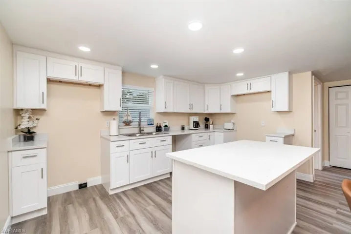Kitchen featuring white cabinetry, a center island, light wood finished floors, recessed lighting, and light countertops
