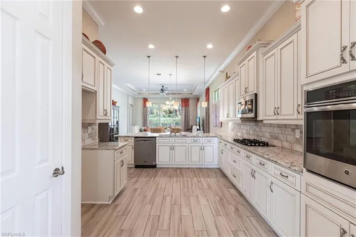 Kitchen featuring decorative backsplash, ornamental molding, a peninsula, stainless steel appliances, and pendant lighting