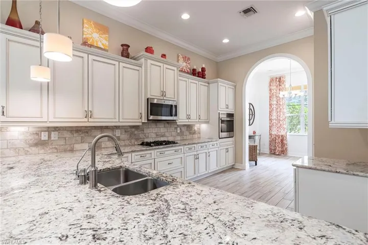 Kitchen featuring a double sink, appliances with stainless steel finishes, decorative backsplash, and pendant lighting