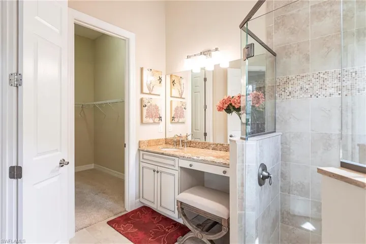 Bathroom featuring a walk in closet, a shower stall, vanity, and tile patterned floors