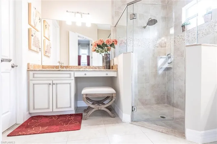 Full bathroom featuring tile patterned flooring, baseboards, a shower stall, and vanity