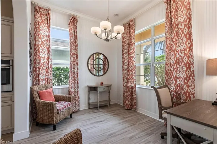 Office/den with baseboards, crown molding, light wood-style tile flooring, a wealth of natural light, and a notable chandelier
