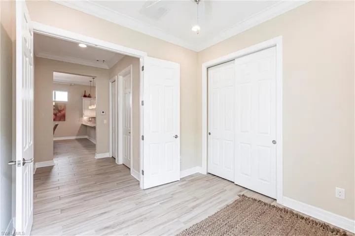 Unfurnished bedroom with ornamental molding, light wood-type flooring, a closet, and baseboards