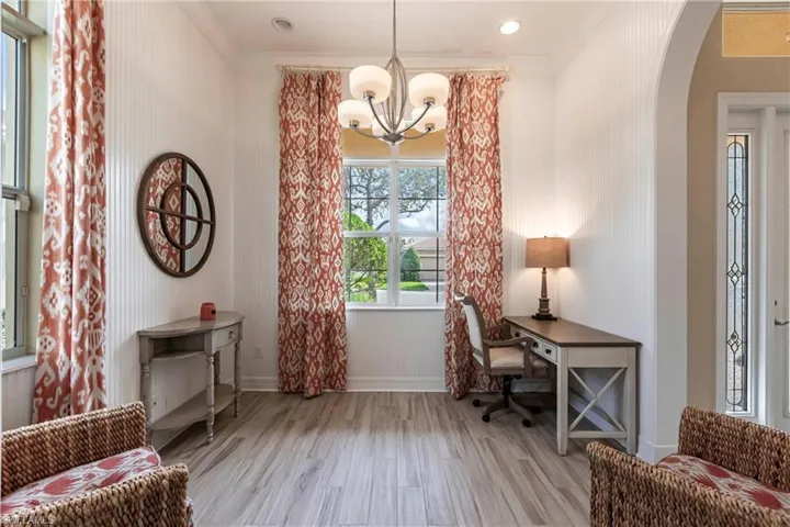 Office/den  area featuring light wood finished floors, baseboards, arched walkways, and ornamental walls.