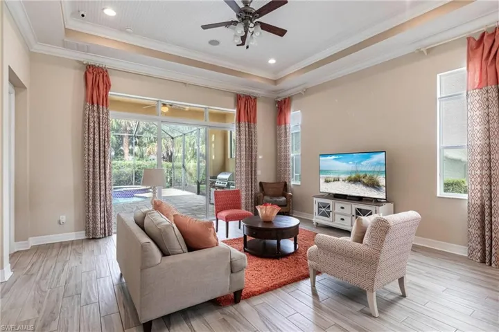 Living room featuring light wood-style tile flooring, a raised ceiling, and a wealth of natural light