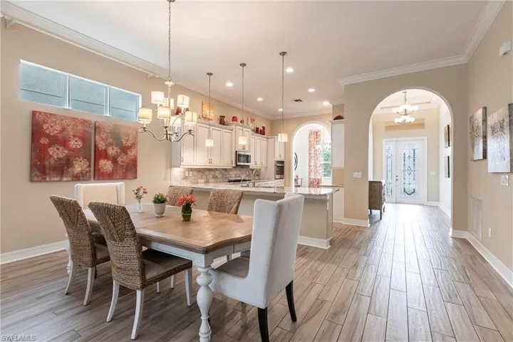 Dining room featuring arched walkways, light wood-tile flooring, baseboards, and an inviting chandelier