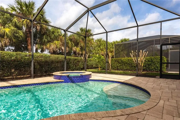 View of pool with a pool with connected hot tub, screen enclosure, and a patio